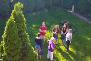 Aerial view of Backyard BBQ attendees chatting outside near a tree.