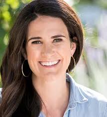 Young woman smiling into camera in front of blurred background