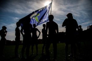 New Trier Cross Country team holds up New Trier flag