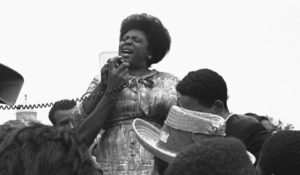 Fannie Lou Hamer with a microphone speaking to a crowd.