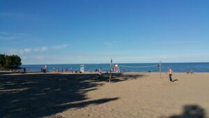 Image of Lee Street Beach, blue water and sky in background, tan sand in foreground.