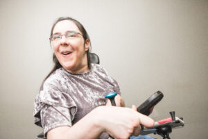 Sarah smiles during a photoshoot wearing a lavender shirt and using her wheelchair.