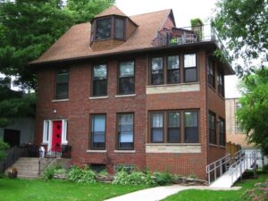 A square brown house with red door that is one example of housing options for people with disabilities.