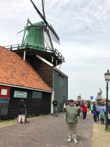 Jonathan stands to the right of a green windmill in Amsterdam