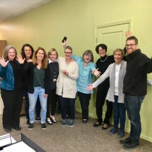 Staff poses to welcome a family group attending New Futures Initiative training to create housing for people with disabilities