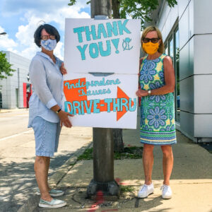 Ann & Niki hold a sign saying "Thank You Independent Futures Drive-Thru" while wearing masks