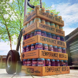 Cases of Temperance Beer stacked on top of each other with a beautiful summer sky in the background.