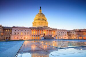 A photo of the Capitol building at night against a clear blue evening sky.