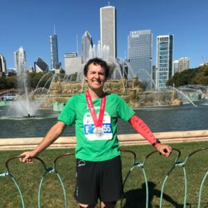 A Chicago Marathon runner poses in front of the Chicago skyline after the race